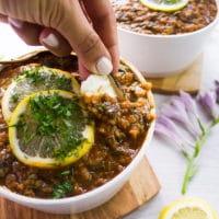 a hand scooping up some lentil stew with a piece of naan bread showing the texture