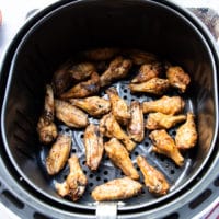 Fully Cooked chicken wings in an air fryer basket