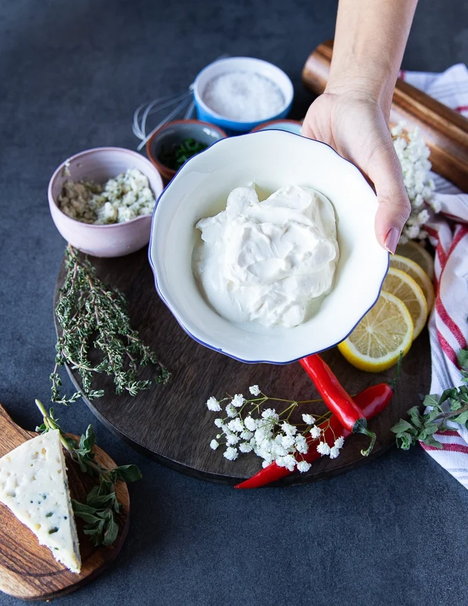 A hand holding a bowl of sour cream