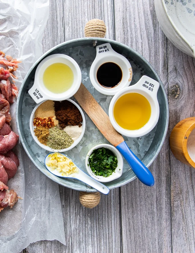 fajita marinade ingredients on a tray including oil, lime juice, dry spice blend, fresh garlic, fresh cilantro in small bowls