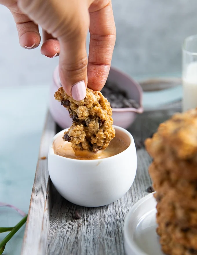 a hand dipping the oatmeal cookie recipe into a cup of espresso