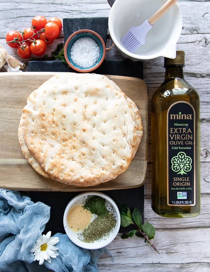 ingredients to make pita chips Thick Greek pita bread on a wooden board to be cut up into pita chips
