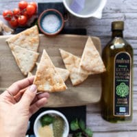 A hand holding a perfect slice of pita chip cut up from pita bread