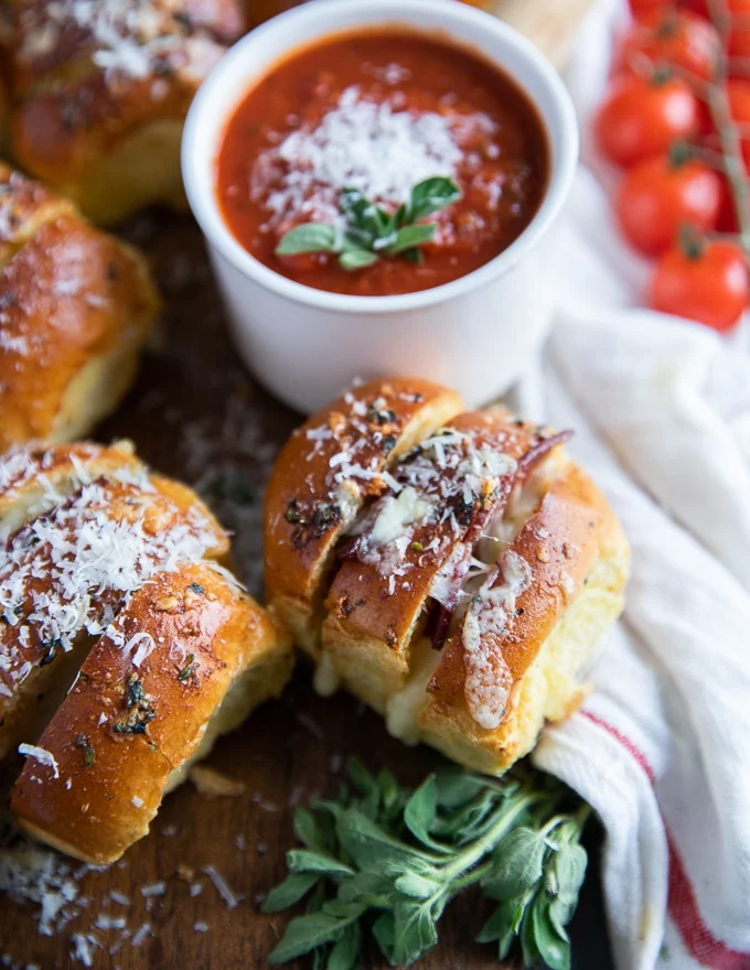 close up of a pizza roll surrounded by fresh basil leaves and sprinkled with parmesan cheese