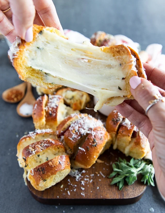 two hands puling apart a pizza roll showing the stretchy cheese