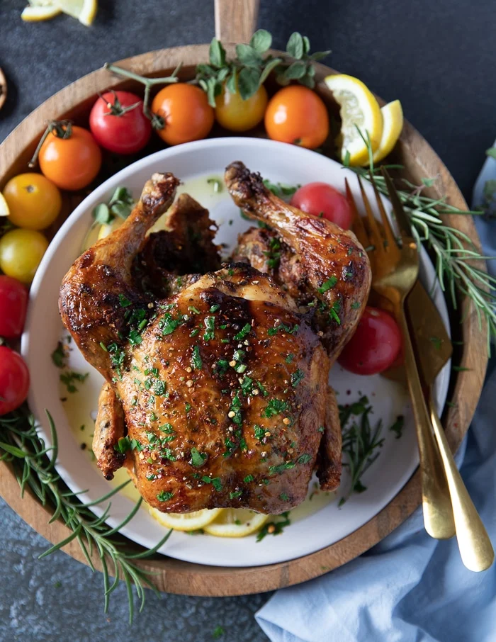 Air fryer whole chicken served on a plate with some parsley on top with crispy skin and perfectly cooked