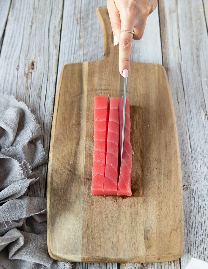 a hand cutting up the tuna steak using a knife