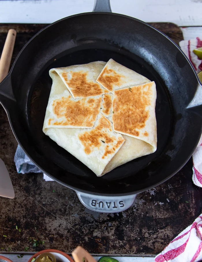 folded over crunchwrap supreme in the skillet showing the golden top