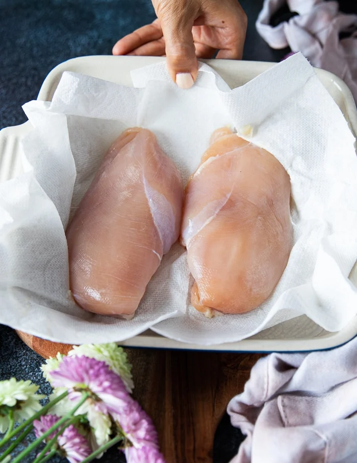 chicken breast after brining are place3d over a kitchen towel to pat dry before seasoning