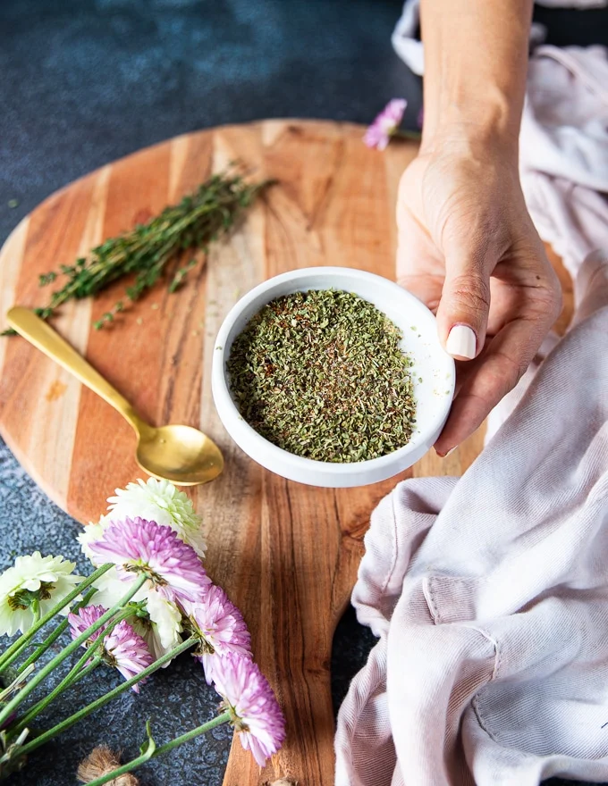 A hand holding a plate of the dry spice blend ready to flavor the chicken breast