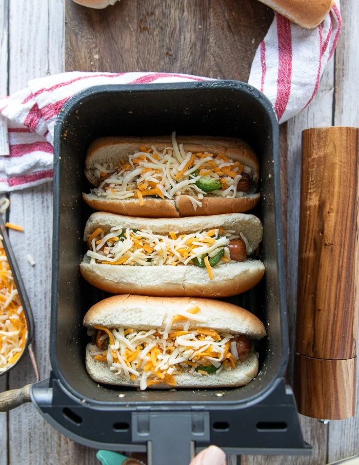 placing the cheesy hot dogs back in the air fryer to melt the cheese