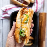 A hand holding a cheesy hot dog bun