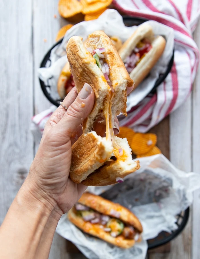 a hand breaking an air fryer hot dog in a bun in half