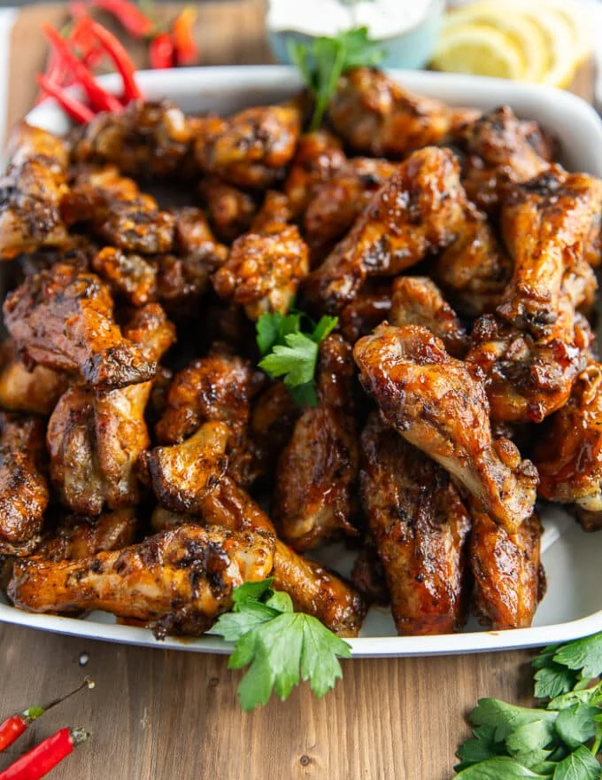 close up of grilled chicken wings showing the crispy skin and the sauces coating them