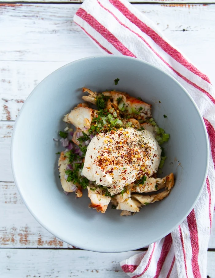 lobster and other lobster tail ingredients added into a large bowl including the mayo, celery, onions, celery, lemon juice and parsley