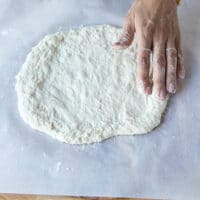 Stretching the no-knead pizza dough before baking.