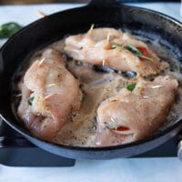 caprese chicken searing in a hot skillet with butter, top side down