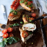 A hand holding a cut up piece of chicken caprese showing how juicy it is
