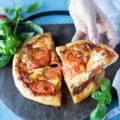 A hand holding a slice of perfectly cooked air fryer pizza