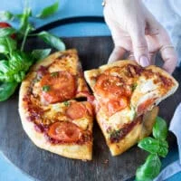 A hand holding a slice of perfectly cooked air fryer pizza
