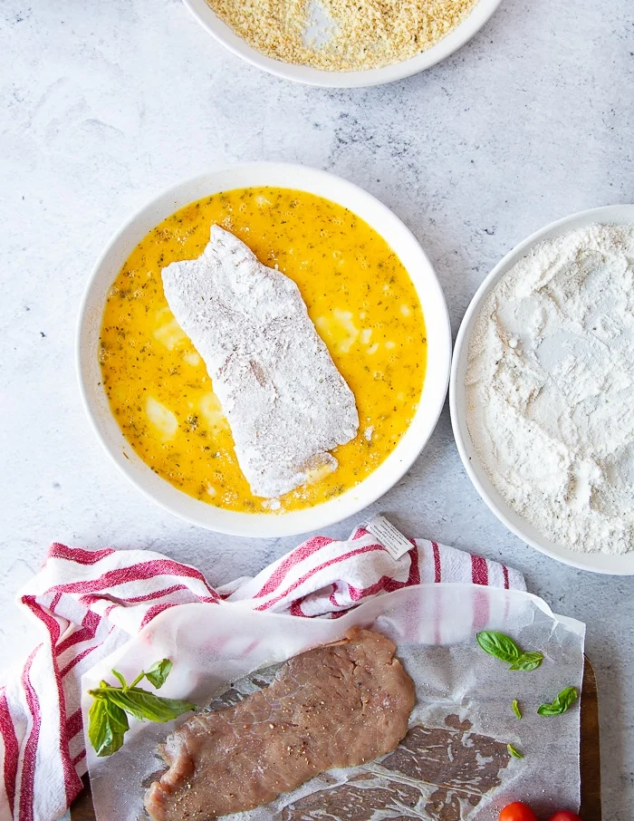 the floured veal cutlet added to the egg plate for coating