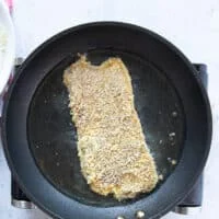 pan searing the breaded veal cutlet in a hot pan with oil