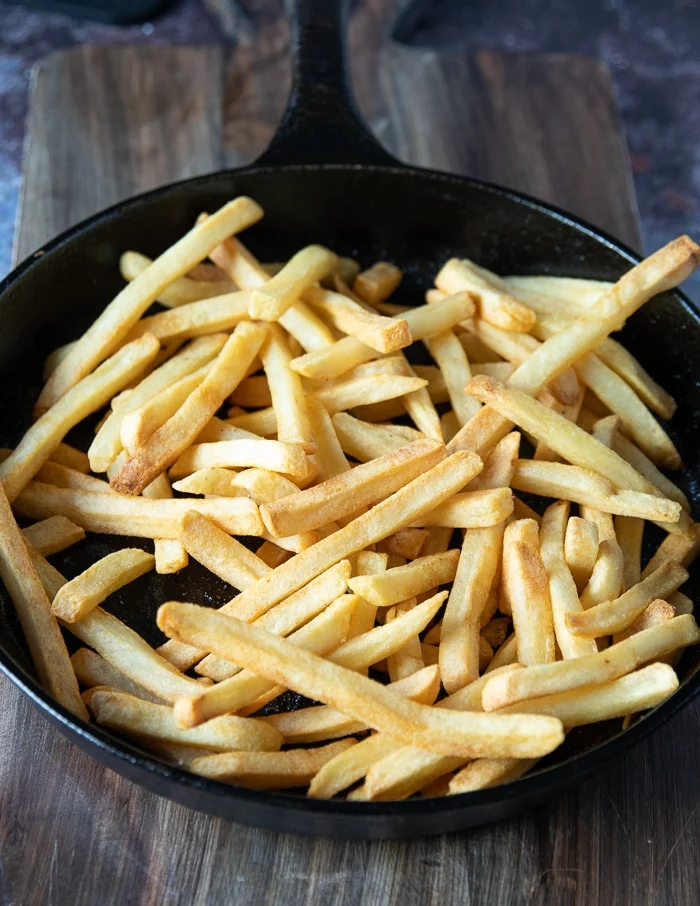 cooked fries are added to the skillet where the meat was seared