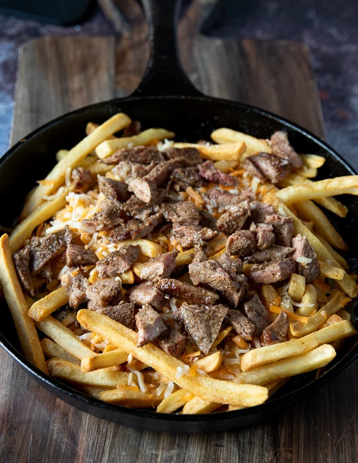 cut up chunks of meat is added over the cheese on the fries to make carne asada fries recipe