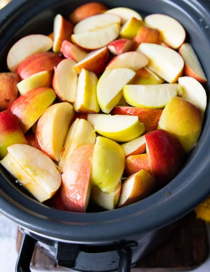 A large crock-pot filled with water, apples, oranges, whole spices, ready to make crock-pot apple cider