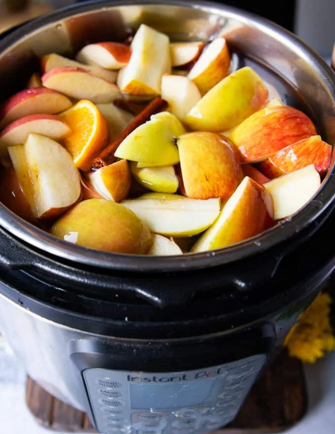 Instant Pot with water, apples, oranges, whole spices to make Homemade Apple Cider