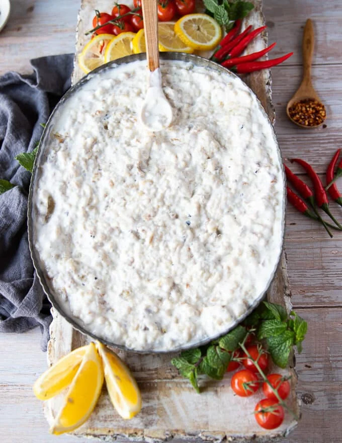 The yogurt sauce is added and blended over the charred eggplant on a serving plate