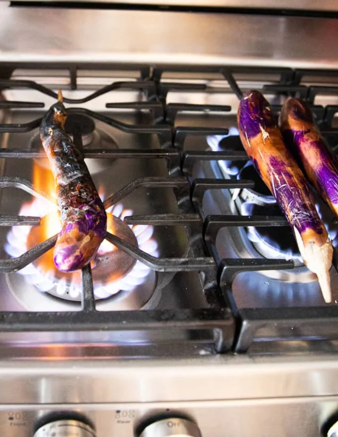 The eggplants placed directly over the flame of a stove (or BBQ)