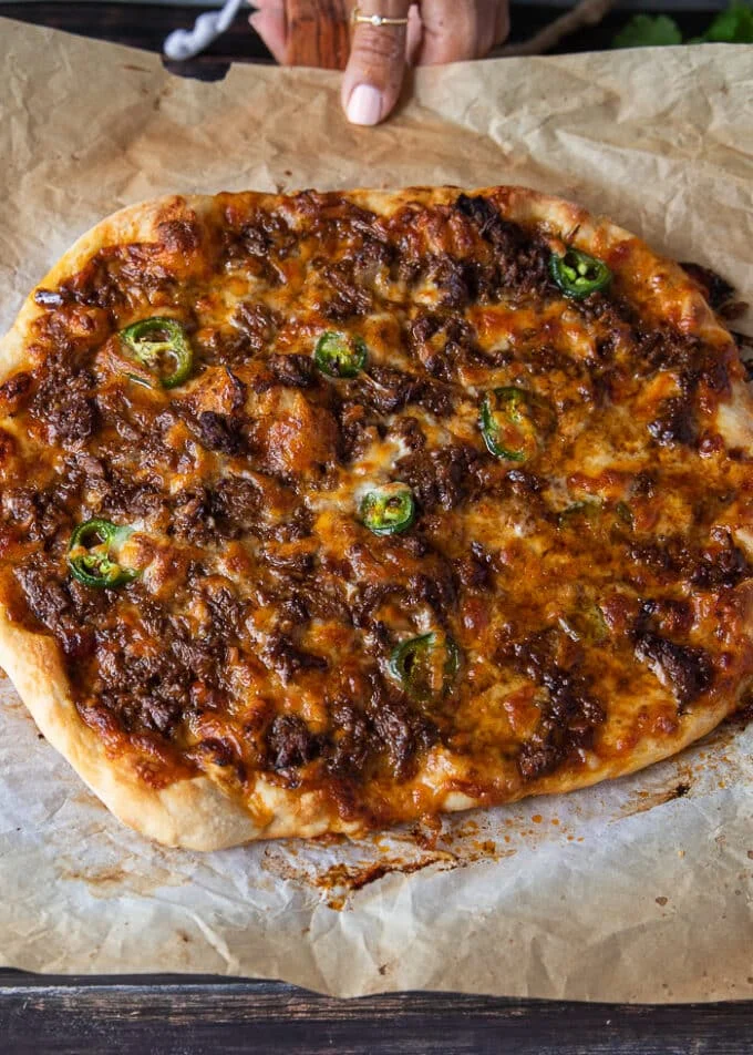 birria pizza out of the oven, ready for more toppings