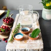 brine ingredients for turkey tenderloin recipe including water, a small bowl of salt, small bowl of sugar, whole bay leaves and whole peppercorns
