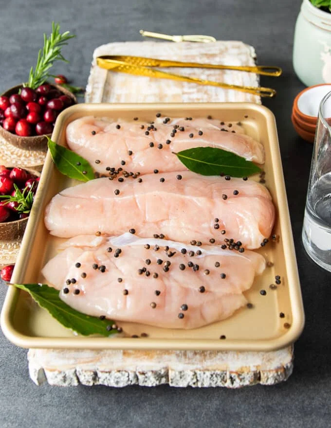 Turkey tenderloins in a deep plate with the brine added and some whole pepper corns