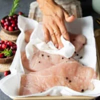A hand patting dry the turkey tenderloin after brining
