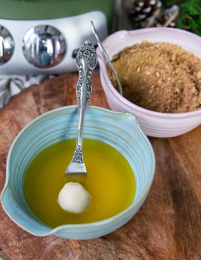 The ball of monkey bread dough is dipped into a bowl of melted butter