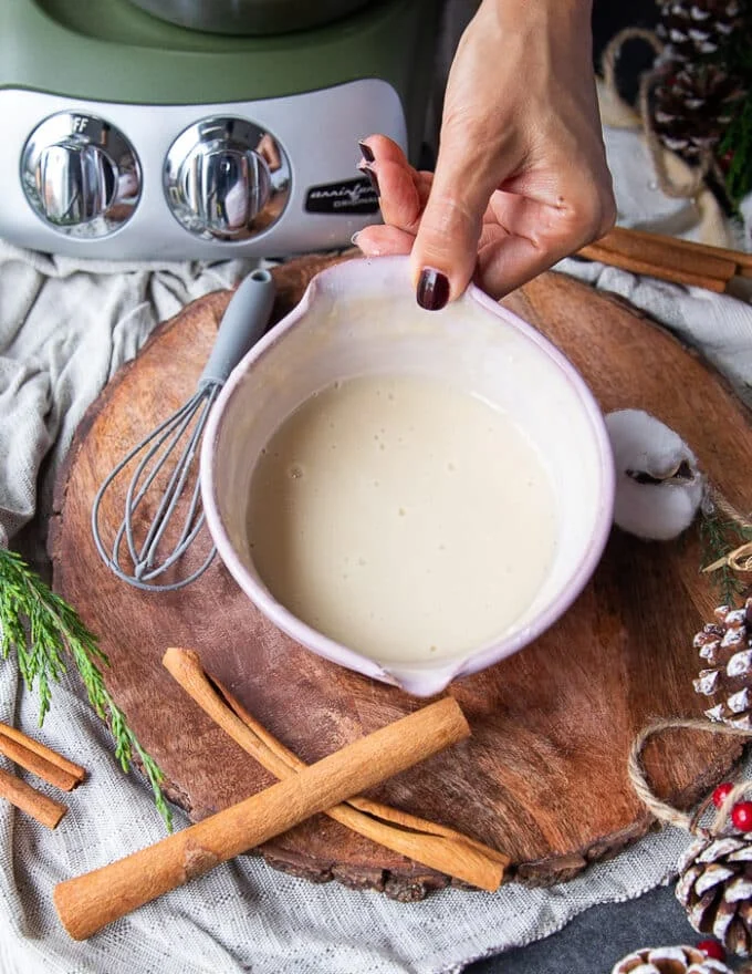 A hand holding a bowl of cream cheese icing