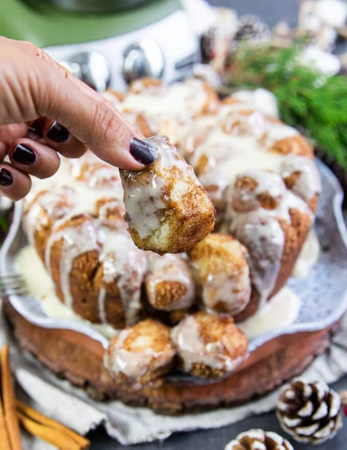 A hand holding a piece of cinnamon roll monkey bread showing how soft it is