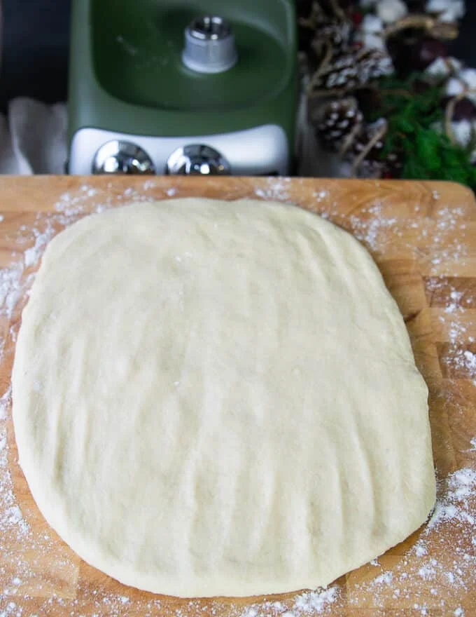 the monkey bread dough is patted down into a rectangle over a wooden board