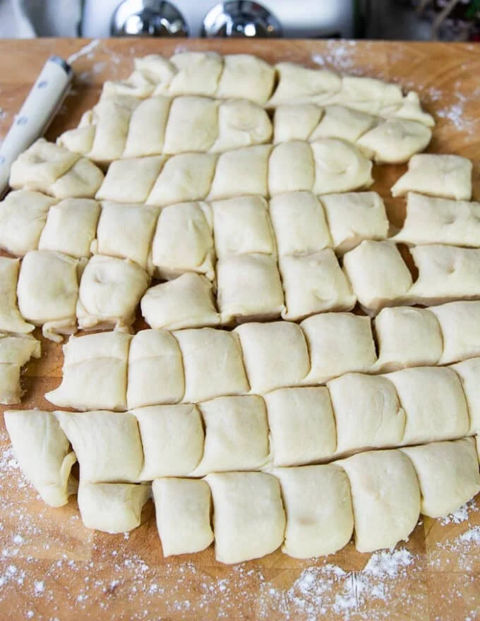 The patted dough is cut into 1 inch squares
