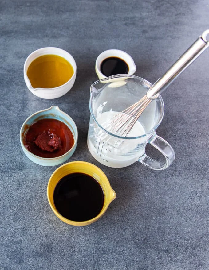 The wet mixture to marinade the lamb with including a bowl of yogurt, some turkish pepper paste, some soy sauce, balsamic vinegar, olive oil and pomegranate molasses