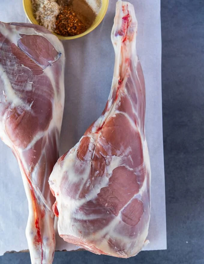 Two fresh Legs of lamb on a cutting board, trimmed