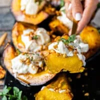 A hand holding a cut up piece of roasted acorn squash to show the texture