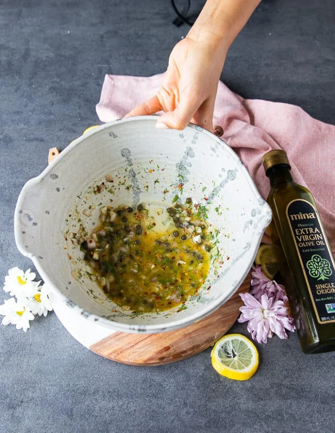 the marinade or flavoring ingredients for the salmon tartare is mixed into a large bowl .