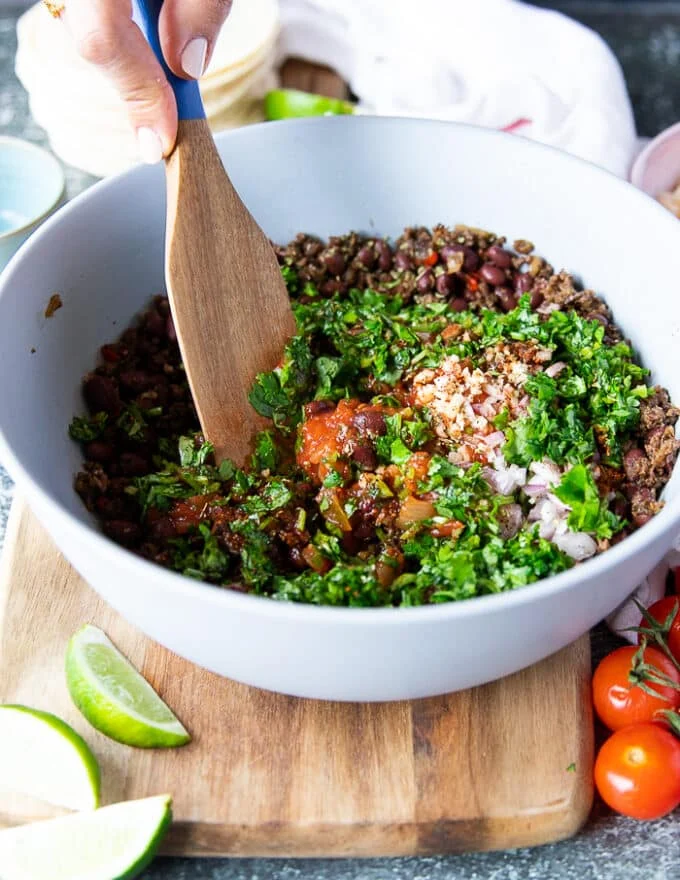 The first step to make taquitos is to prepare the filling, so a bowl with cooked beef has some salsa, cilantro, garlic and onions added to it