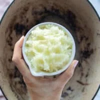 A hand holding a bowl of onions