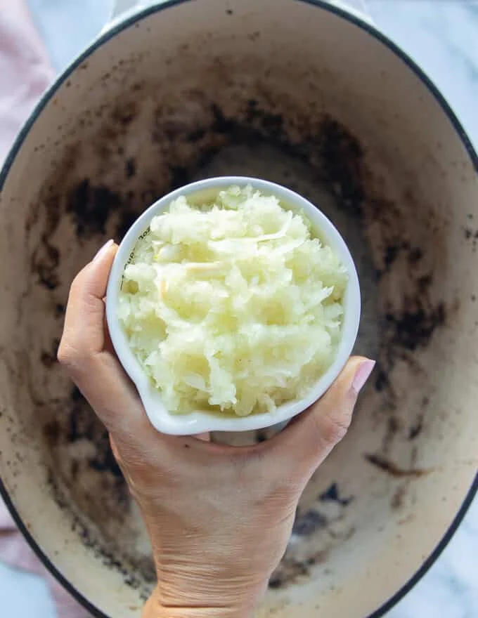 A hand holding a bowl of onions
