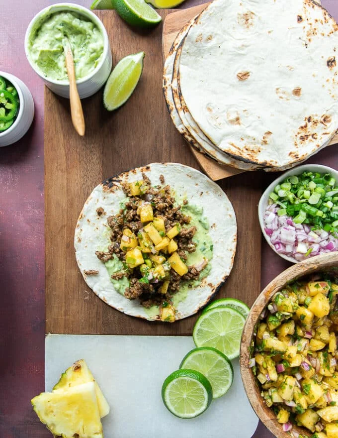 Assembling the tacos now by adding more pineapple salsa over the taco meat