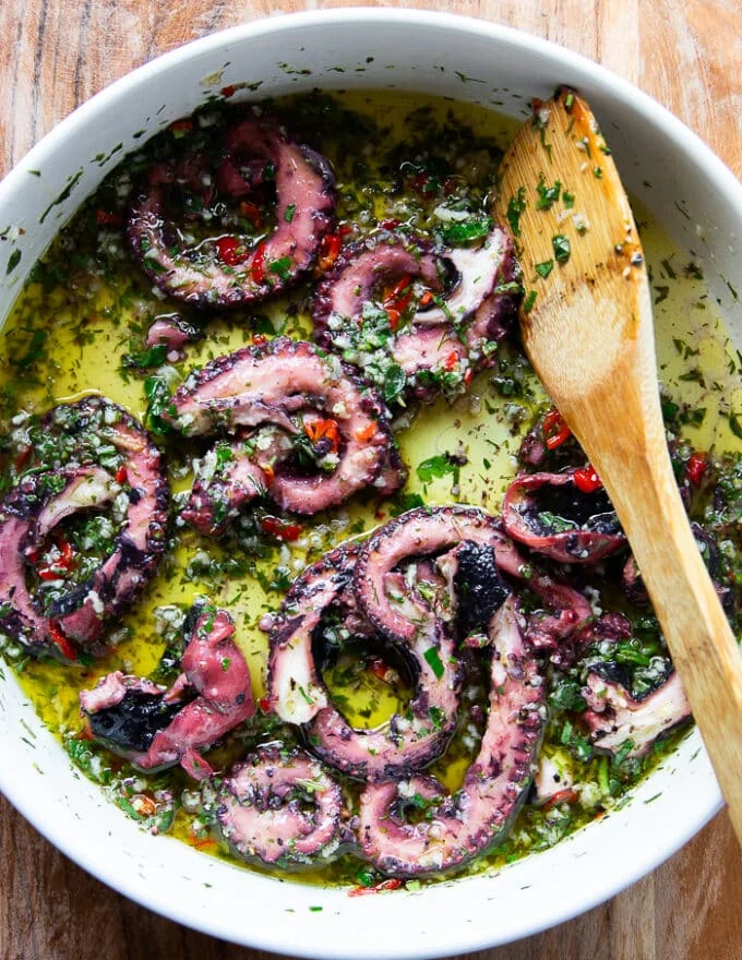 The cooked octopus added to the marinade and tossed to coat